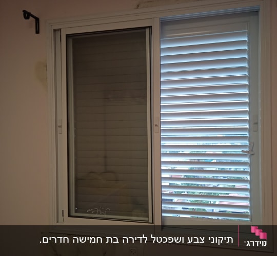 חלון עם תריסים, קיר עם סימני תיקון